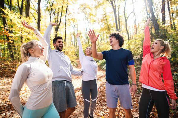 Happy Group Of Runners Smiling And Stacking Hands While Standing