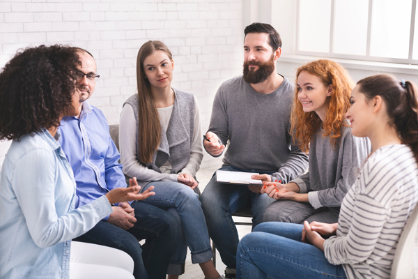 Man Psychiatrist Talking With Patients At Rehab Group Meeting